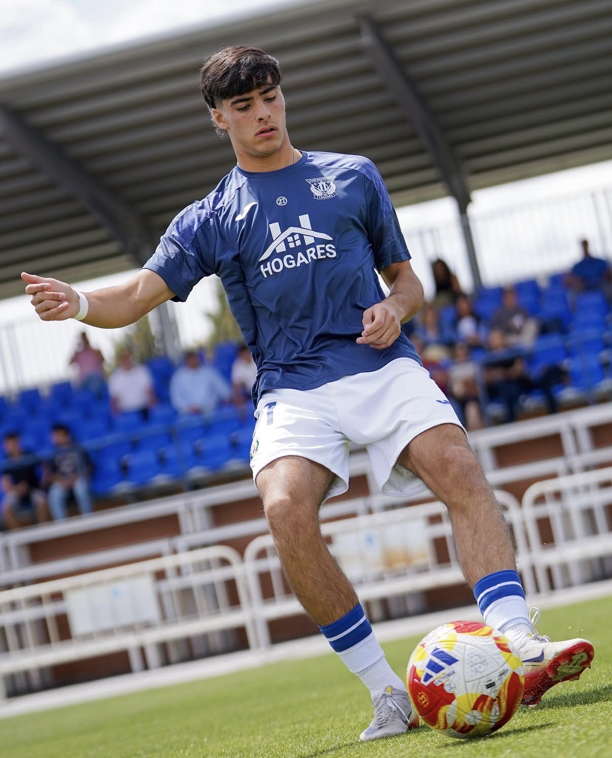 Jugador conduciendo el balón en el campo con la equipación del C.D. Leganés